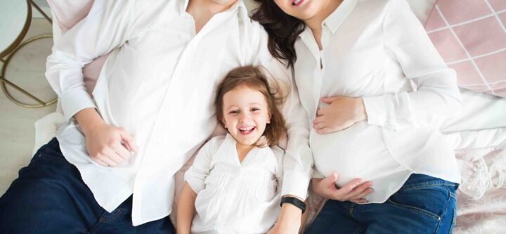 Happy pregnant woman with her husband and little daughter