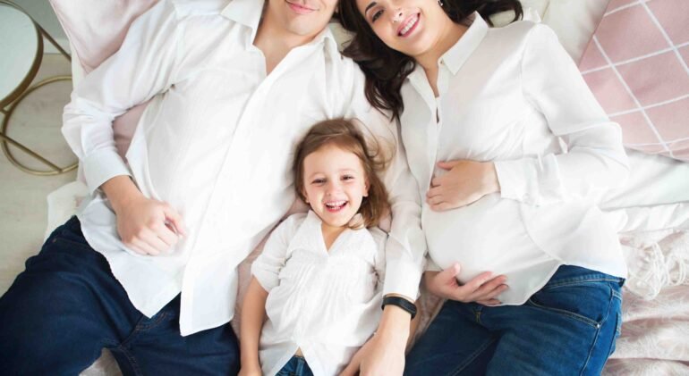 Happy pregnant woman with her husband and little daughter