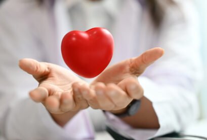 Red heart floating over opened hands. Health care, cardiological, medical and charity concept.